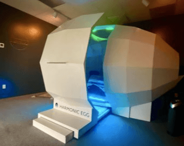 The image shows the Harmonic Egg, which is a chamber that you sit in to help sync your cells naturally.