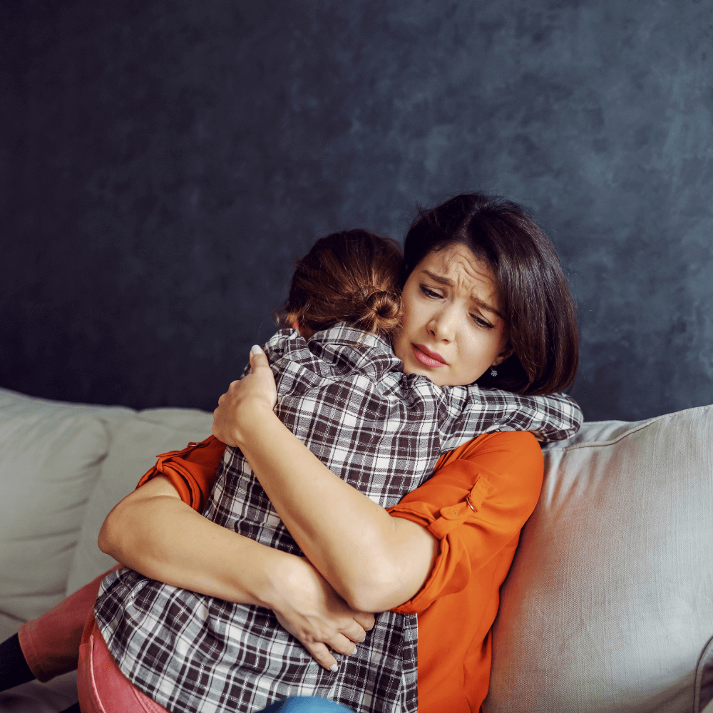a woman with a stressed look on her face hugging a young boy