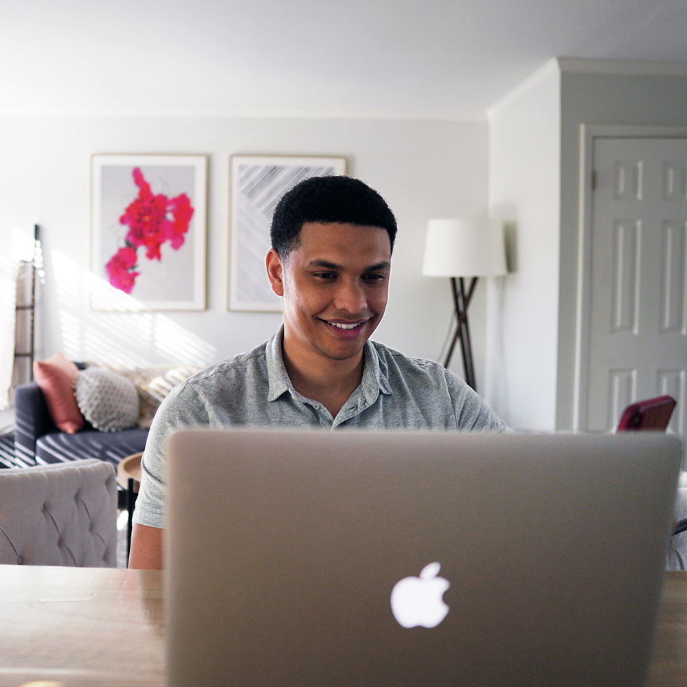 this photo shows a black man smiling on his computer